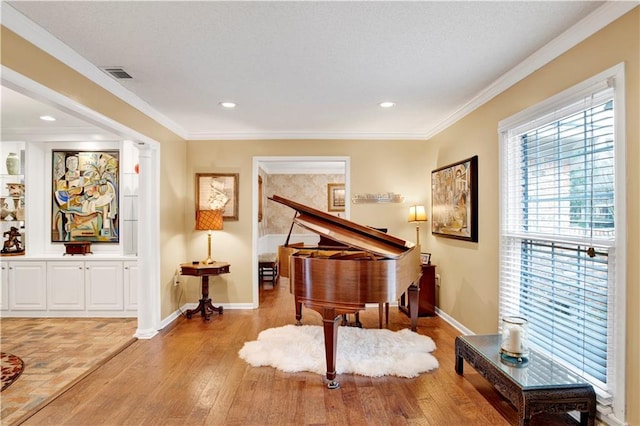 miscellaneous room with decorative columns, ornamental molding, and light wood-type flooring