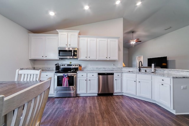 kitchen with white cabinets, a peninsula, appliances with stainless steel finishes, and lofted ceiling