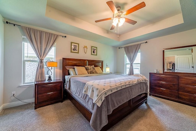 bedroom featuring baseboards, carpet flooring, a ceiling fan, and a tray ceiling