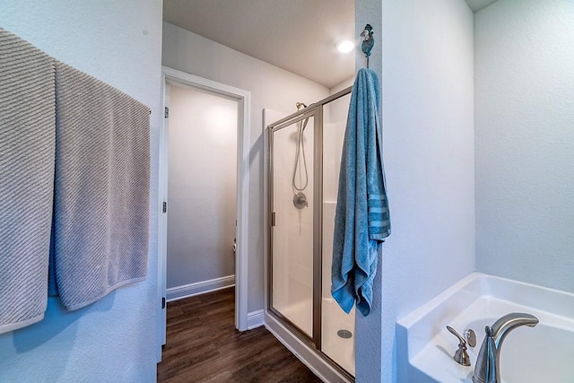 full bath featuring a bath, wood finished floors, and a shower stall