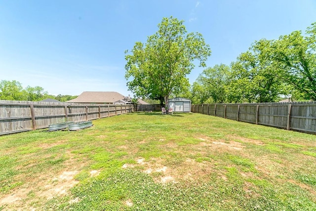 view of yard with an outdoor structure, a fenced backyard, and a storage unit