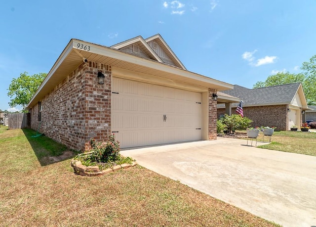 view of side of property with a garage, a yard, driveway, and brick siding
