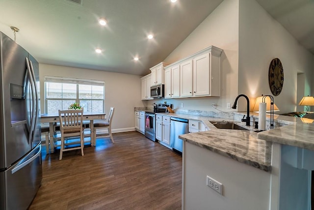 kitchen featuring light stone counters, a sink, dark wood finished floors, vaulted ceiling, and stainless steel appliances