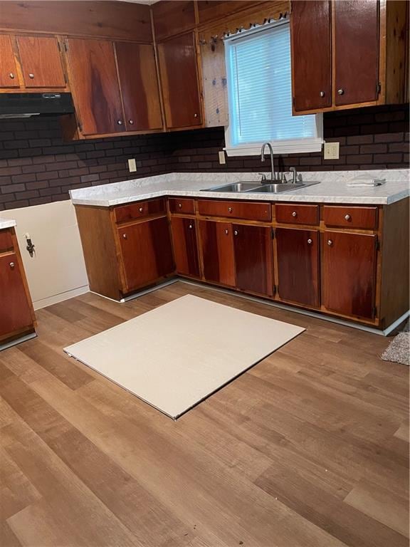 kitchen with sink, range hood, decorative backsplash, and light wood-type flooring