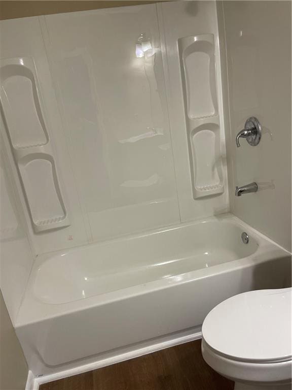 bathroom featuring hardwood / wood-style flooring, toilet, and shower / bathtub combination