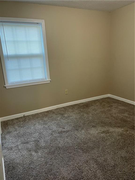 carpeted empty room with a textured ceiling