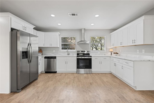 kitchen featuring a sink, wall chimney exhaust hood, appliances with stainless steel finishes, light wood-type flooring, and visible vents