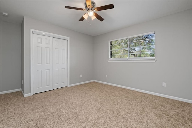 unfurnished bedroom featuring a closet, a ceiling fan, baseboards, and carpet
