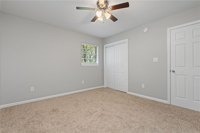 unfurnished bedroom featuring baseboards, a closet, light colored carpet, and ceiling fan