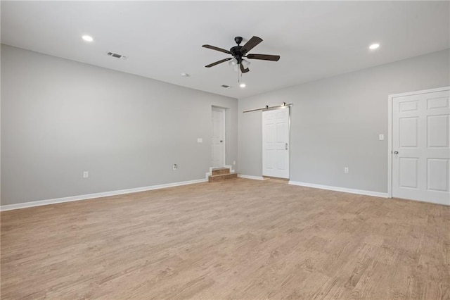 empty room with light wood-style flooring, recessed lighting, baseboards, a barn door, and a ceiling fan