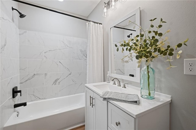 full bath with a textured wall, shower / bath combo with shower curtain, and vanity