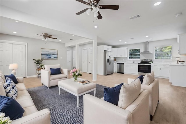 living room featuring light wood-style flooring, visible vents, baseboards, recessed lighting, and a ceiling fan