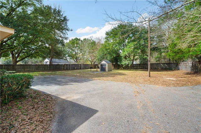 view of yard with a fenced backyard, an outbuilding, a patio area, and a storage shed