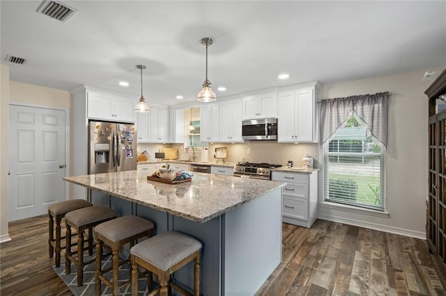 12850 Saeger Rd, Grand Bay, AL 36541 - kitchen featuring appliances with stainless steel finishes, white cabinets, a center island, dark wood-style floors, and a kitchen breakfast bar