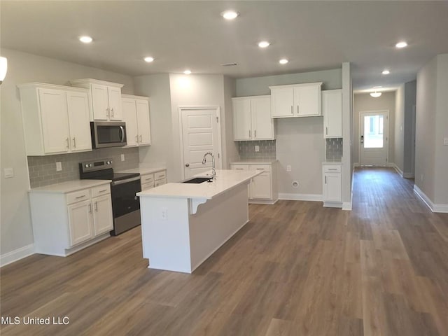 kitchen with white cabinetry, sink, dark wood-type flooring, stainless steel appliances, and a kitchen island with sink