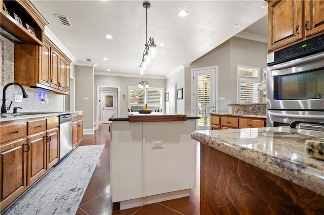 2217 Shandwick Dr, Mobile, AL 36695 - kitchen featuring crown molding, a sink, appliances with stainless steel finishes, a kitchen island, and brown cabinets