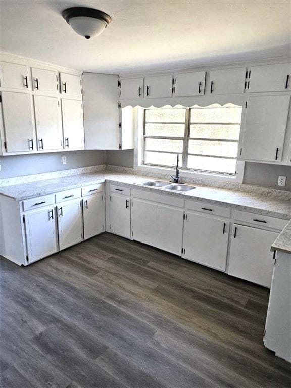 kitchen with light countertops, dark wood finished floors, white cabinets, and a sink