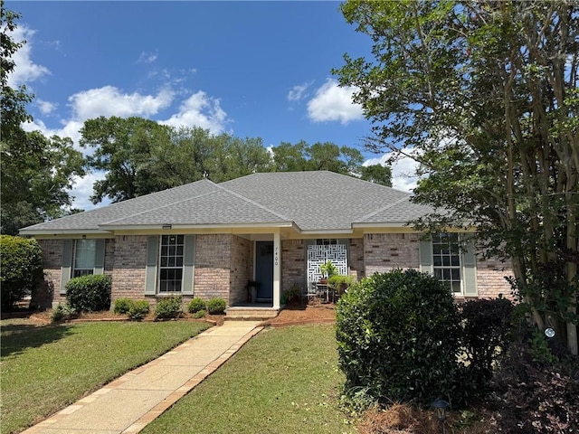 ranch-style home featuring a shingled roof, a front lawn, and brick siding