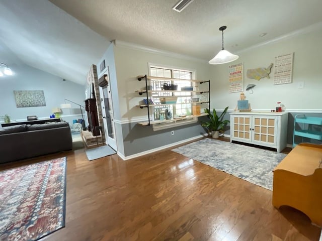 dining room with baseboards, ornamental molding, a textured ceiling, and wood finished floors