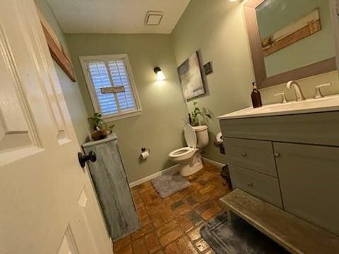 bathroom featuring vanity, stone finish flooring, baseboards, and toilet