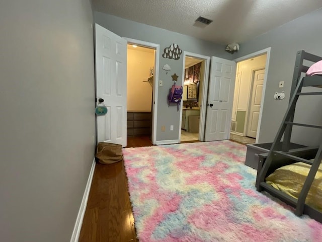 bedroom with baseboards, visible vents, a textured ceiling, and a spacious closet