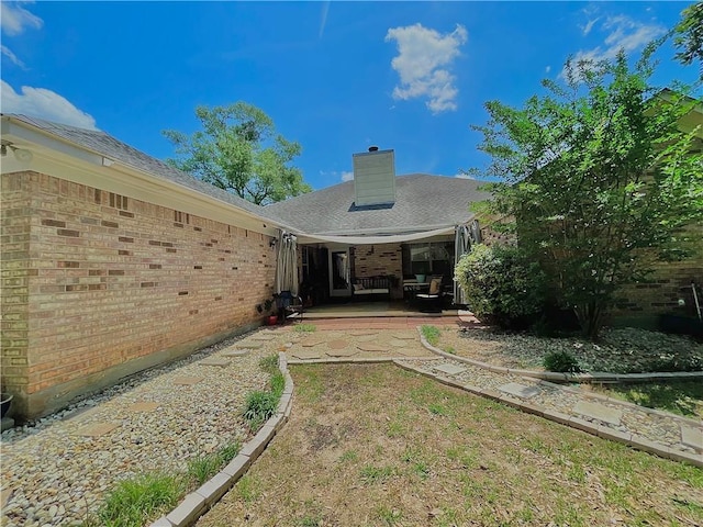 rear view of property with a chimney, a patio area, and brick siding