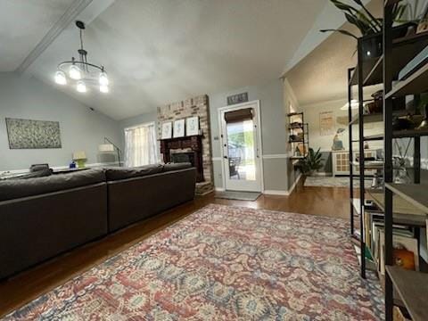 living room featuring baseboards, lofted ceiling with beams, wood finished floors, and a fireplace