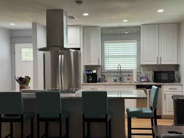 1071 Coke Ct, Mobile, AL 36695 - kitchen with island range hood, stainless steel appliances, a kitchen bar, white cabinets, and recessed lighting