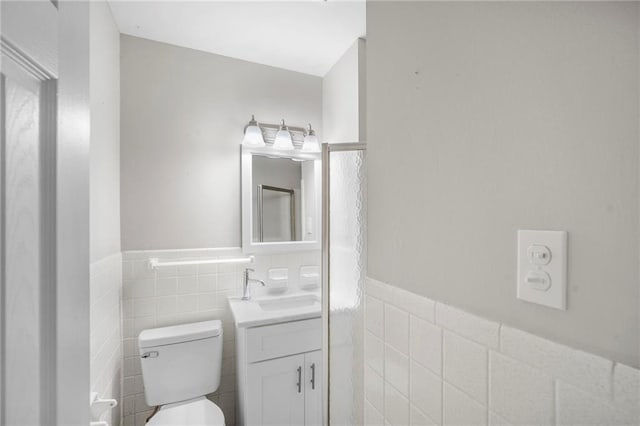 bathroom featuring toilet, vanity, and tile walls