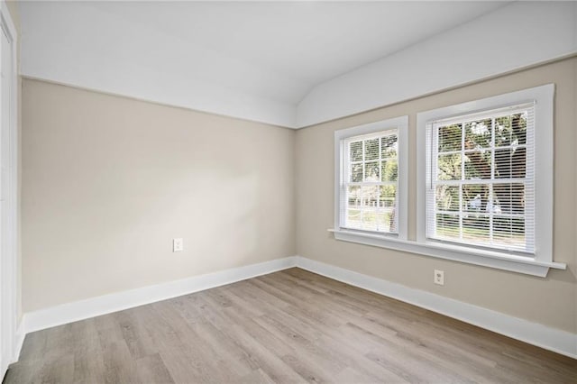 empty room featuring vaulted ceiling and light hardwood / wood-style flooring