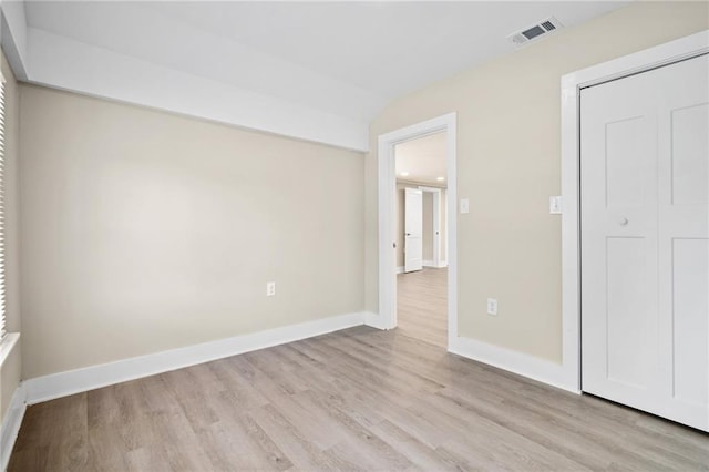 unfurnished bedroom with light wood-type flooring, a closet, and vaulted ceiling