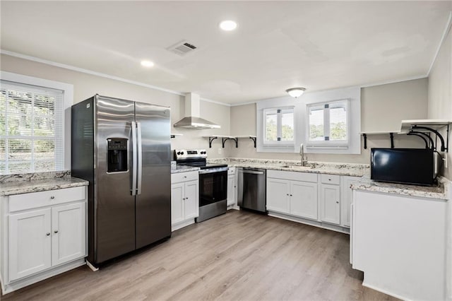 kitchen featuring sink, light wood-type flooring, appliances with stainless steel finishes, white cabinets, and wall chimney exhaust hood