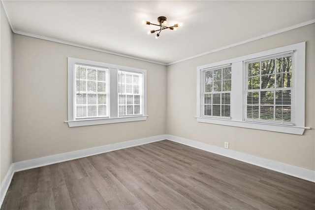 spare room featuring hardwood / wood-style floors, crown molding, and an inviting chandelier