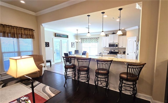 1109 Orlando Dr, Foley, AL 36535 - kitchen with stainless steel appliances, a breakfast bar, white cabinets, crown molding, and baseboards