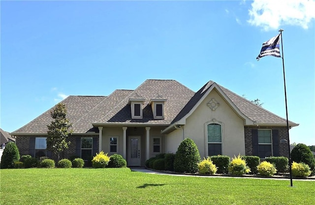 1109 Orlando Dr, Foley, AL 36535 - view of front of house featuring stucco siding, a front yard, a shingled roof, and brick siding