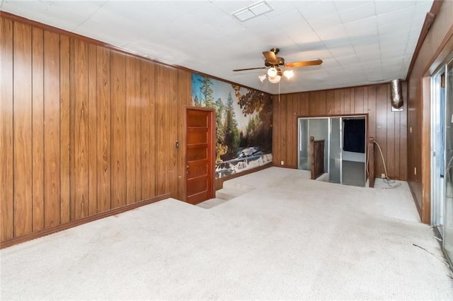 carpeted living room featuring ceiling fan and wood walls