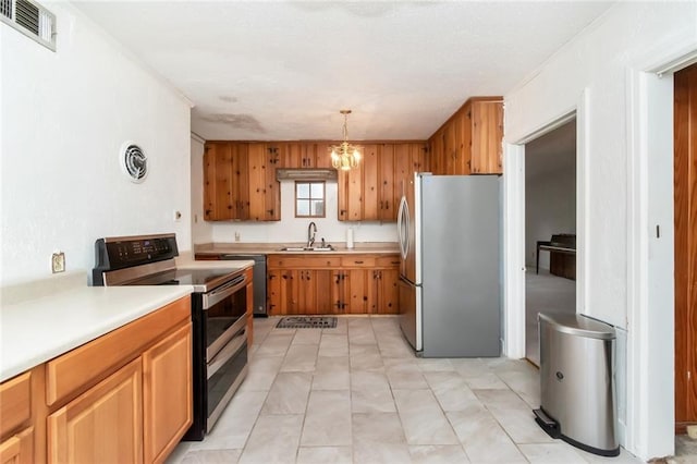 kitchen featuring appliances with stainless steel finishes, decorative light fixtures, a chandelier, and sink