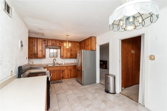 kitchen with range with electric stovetop, a notable chandelier, sink, and stainless steel fridge