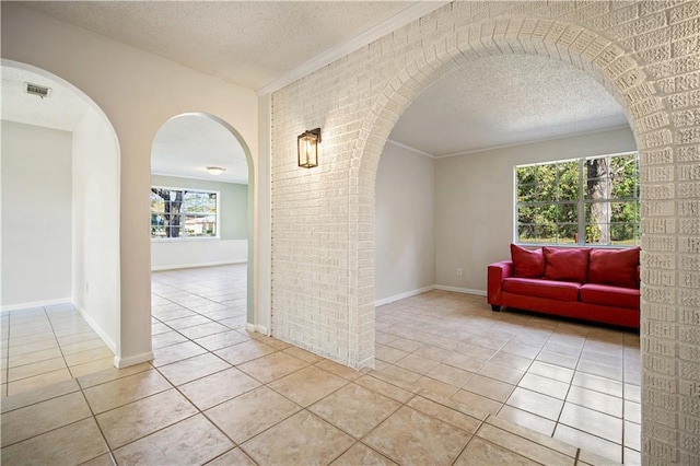 tiled empty room with ornamental molding and a textured ceiling