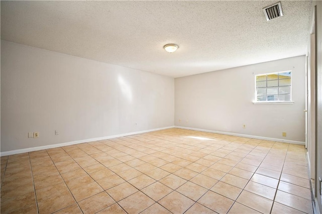 tiled empty room with a textured ceiling