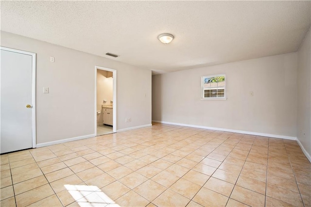 empty room with light tile patterned floors and a textured ceiling