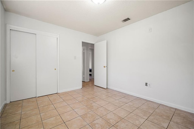 unfurnished bedroom featuring light tile patterned floors, a closet, and a textured ceiling