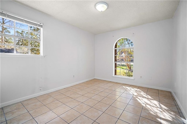 tiled empty room featuring a textured ceiling