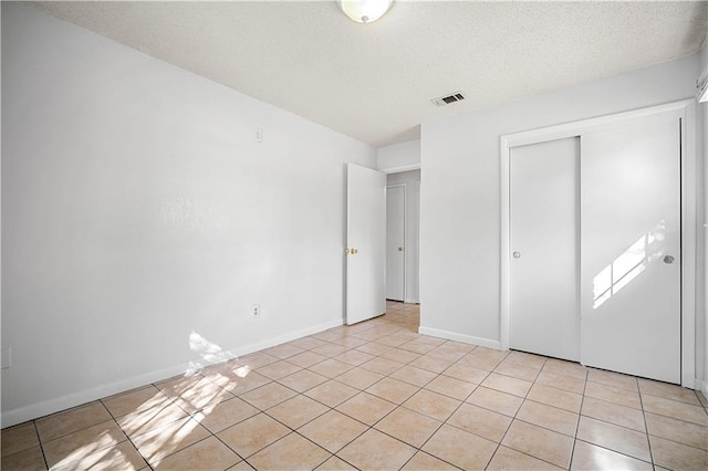 unfurnished bedroom with light tile patterned floors, a textured ceiling, and a closet