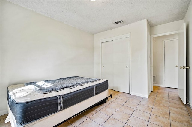 bedroom featuring light tile patterned flooring, a textured ceiling, and a closet