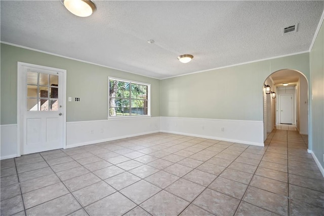 tiled spare room with crown molding and a textured ceiling