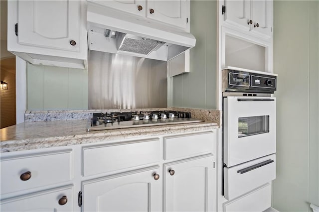 kitchen with stainless steel gas stovetop, white cabinetry, and oven