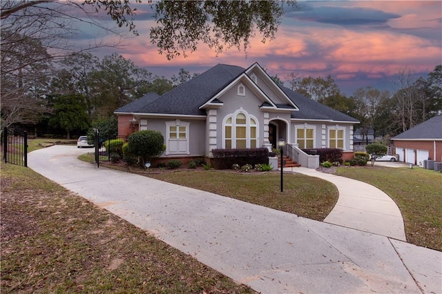 view of front of property with stucco siding, a detached garage, and a lawn