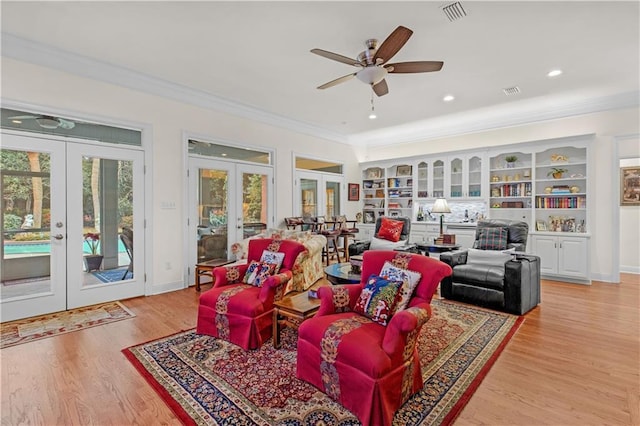 living area featuring french doors, visible vents, ornamental molding, and light wood-style flooring