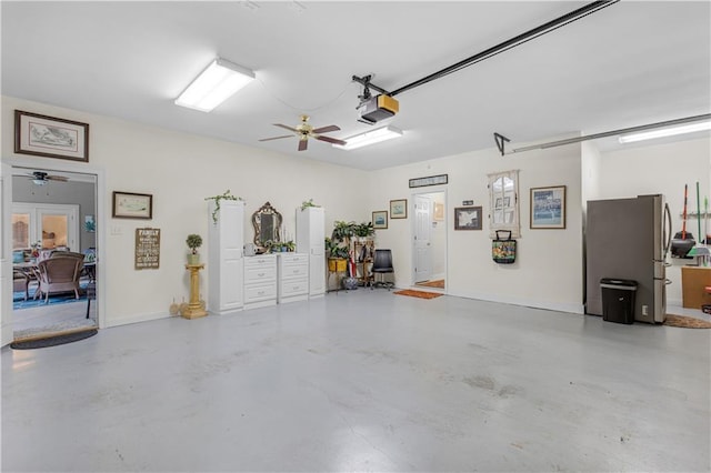 garage featuring a ceiling fan, a garage door opener, freestanding refrigerator, french doors, and baseboards